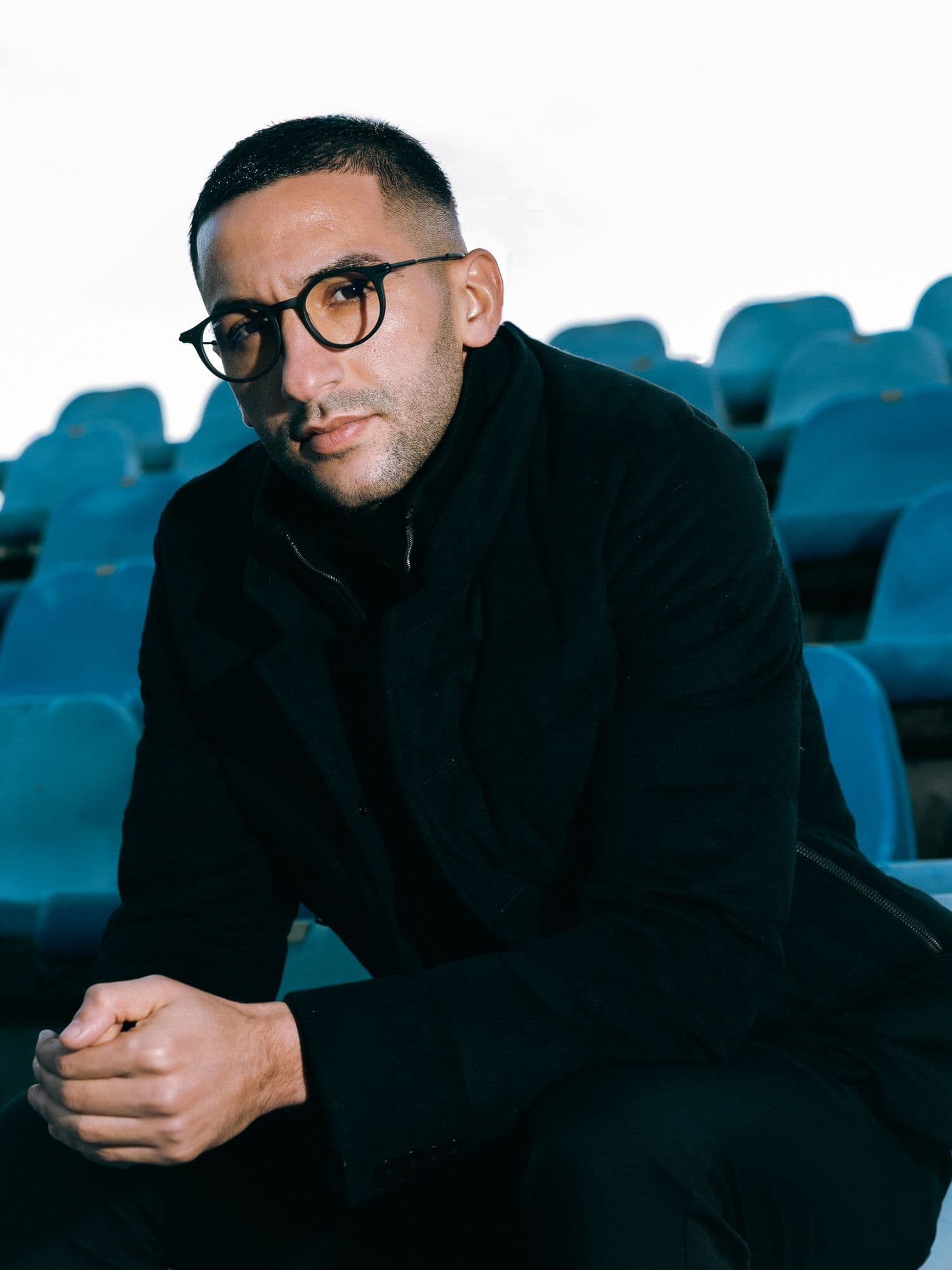 Portrait of a man in a black coat in an empty stadium